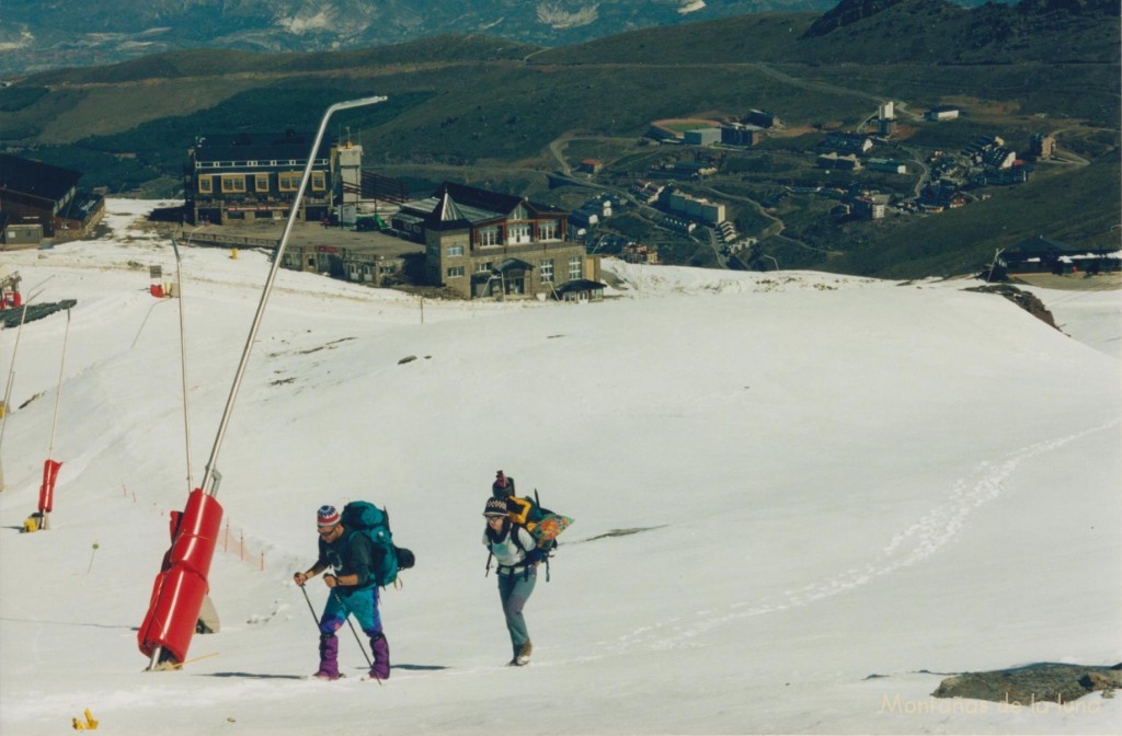 Tomás e Isa cruzando Borreguiles con los hoteles de la estación de esquí detrás